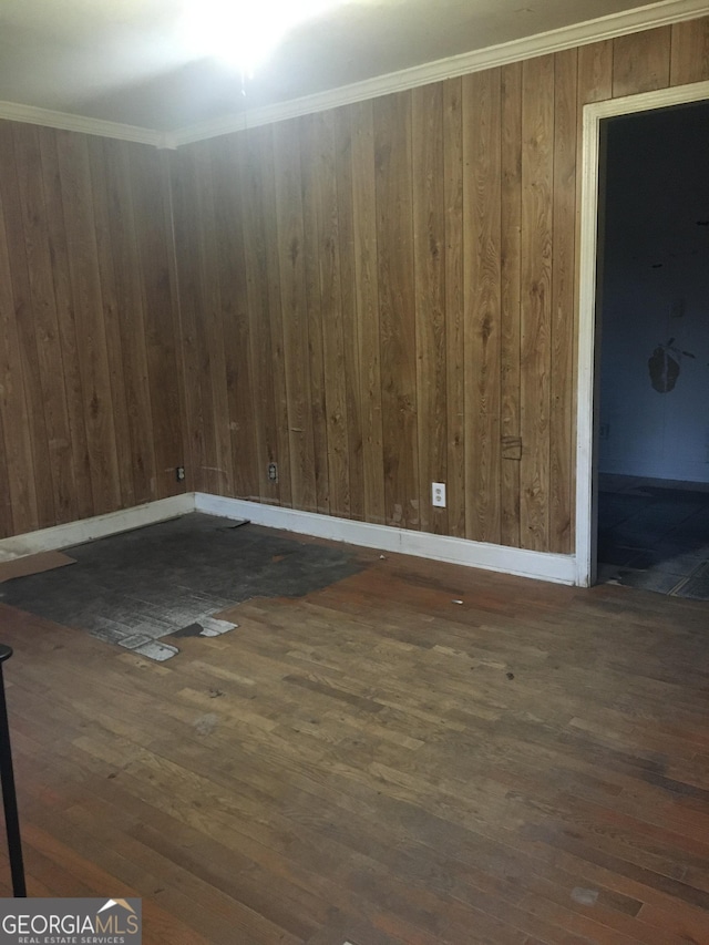 spare room featuring ornamental molding, dark wood-type flooring, and wood walls