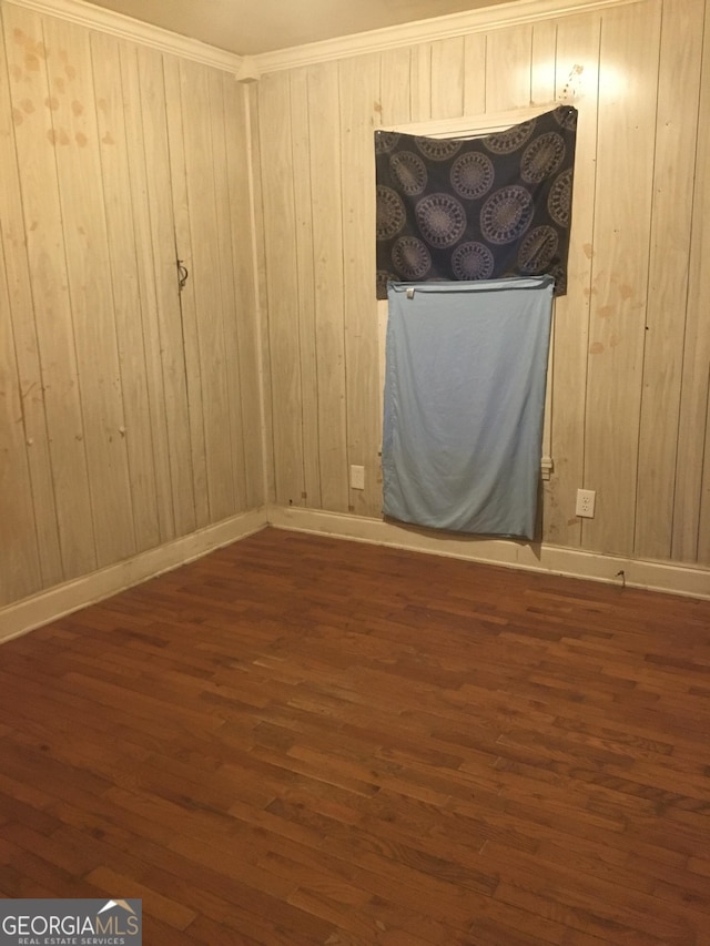 empty room with wood walls, dark hardwood / wood-style flooring, and ornamental molding