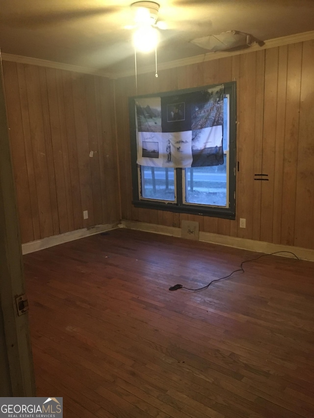 spare room featuring dark hardwood / wood-style floors, crown molding, and wood walls