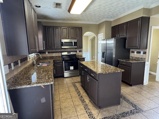 kitchen featuring light tile patterned floors, stainless steel appliances, a kitchen island, and sink