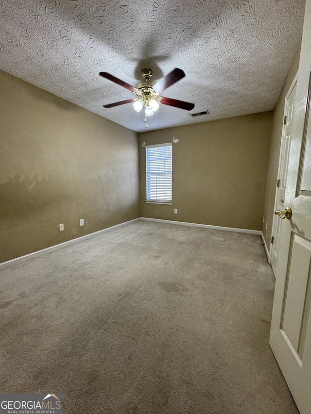 spare room featuring carpet, ceiling fan, and a textured ceiling