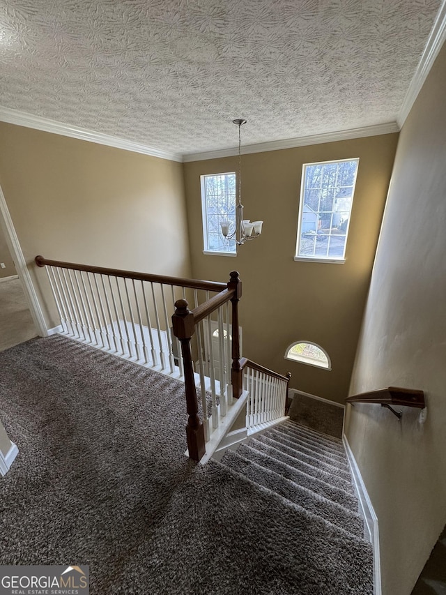 staircase with crown molding, carpet, a textured ceiling, and an inviting chandelier