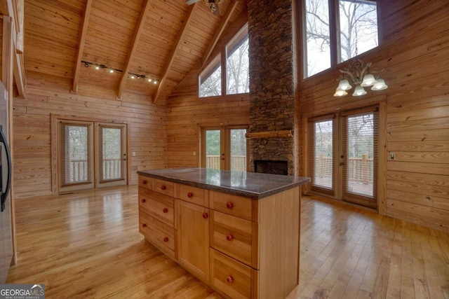 kitchen with french doors, light hardwood / wood-style floors, high vaulted ceiling, and wooden walls