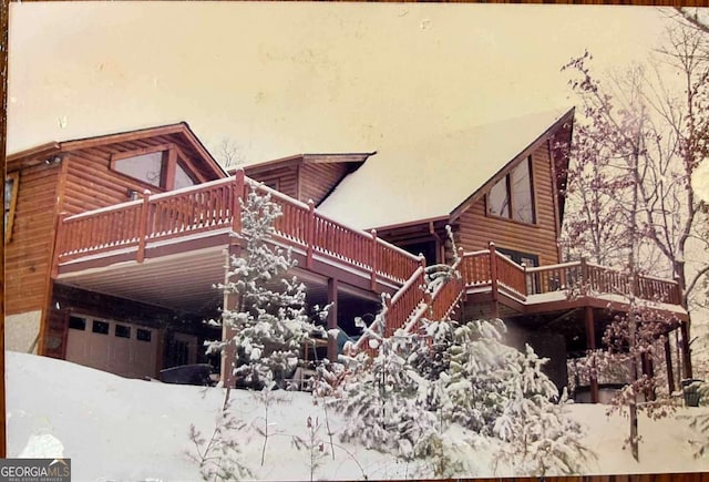 snow covered property with a garage and a deck