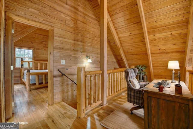 office area with lofted ceiling with beams, wooden ceiling, light hardwood / wood-style flooring, and wooden walls