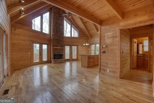 unfurnished living room with light hardwood / wood-style flooring, beamed ceiling, wood ceiling, and french doors