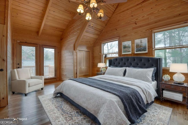 bedroom with hardwood / wood-style floors, beamed ceiling, wooden walls, and multiple windows