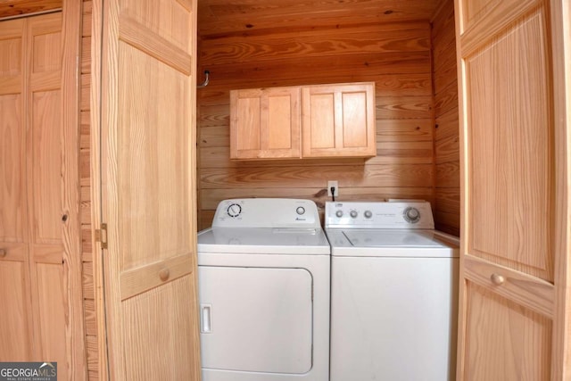 washroom featuring wooden walls, cabinets, and independent washer and dryer