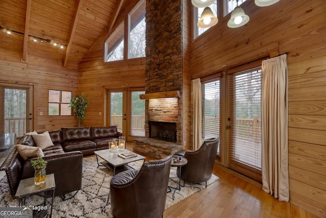 living room featuring beam ceiling, a healthy amount of sunlight, high vaulted ceiling, and light hardwood / wood-style floors