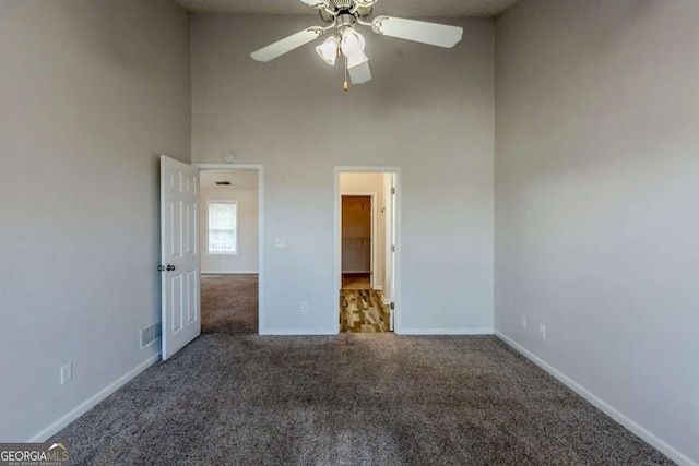 unfurnished bedroom featuring ceiling fan, a towering ceiling, and carpet floors