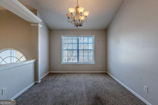 spare room featuring a wealth of natural light, carpet floors, a textured ceiling, and an inviting chandelier