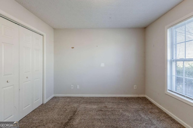 unfurnished bedroom featuring carpet, a textured ceiling, and a closet