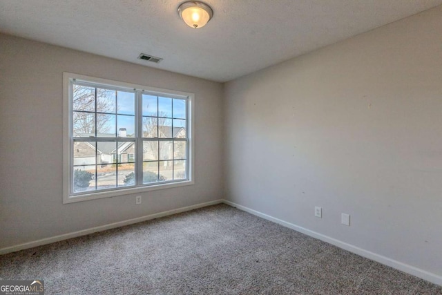 carpeted empty room featuring a textured ceiling