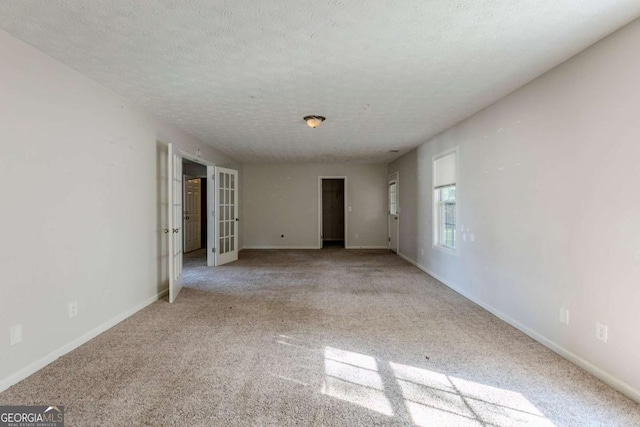 unfurnished room with a textured ceiling and light colored carpet