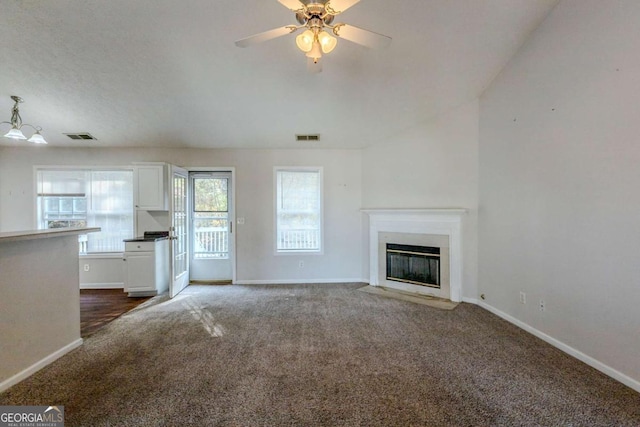 unfurnished living room featuring dark carpet, vaulted ceiling, and ceiling fan