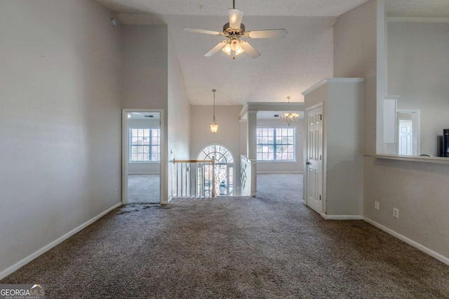 spare room with ceiling fan with notable chandelier, carpet floors, and high vaulted ceiling