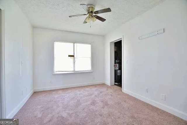 carpeted empty room with a textured ceiling, ceiling fan, and water heater