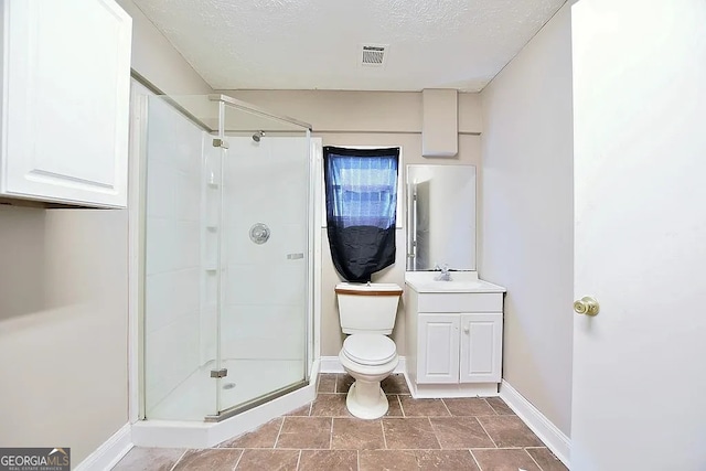 bathroom featuring vanity, toilet, a shower with shower door, and a textured ceiling