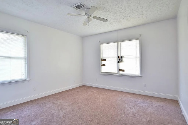 spare room featuring a textured ceiling, ceiling fan, and light carpet