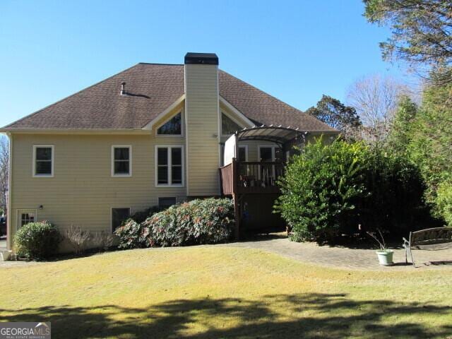 back of property featuring a deck and a yard