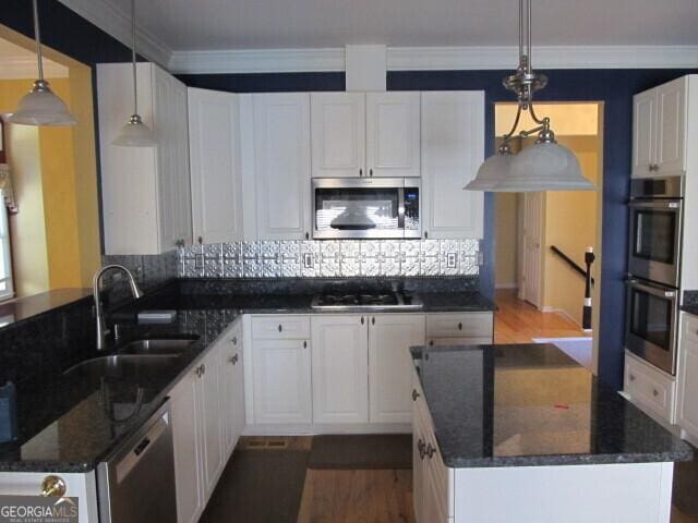 kitchen with decorative light fixtures, stainless steel appliances, white cabinetry, and sink