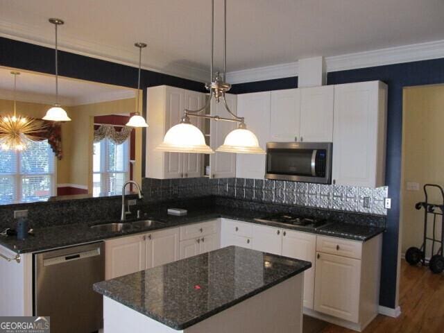 kitchen with tasteful backsplash, stainless steel appliances, sink, pendant lighting, and white cabinetry