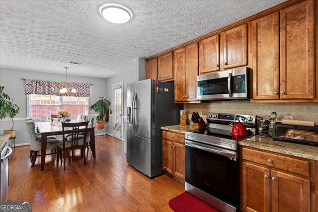 kitchen with sink, light stone counters, dark hardwood / wood-style flooring, stainless steel dishwasher, and a textured ceiling