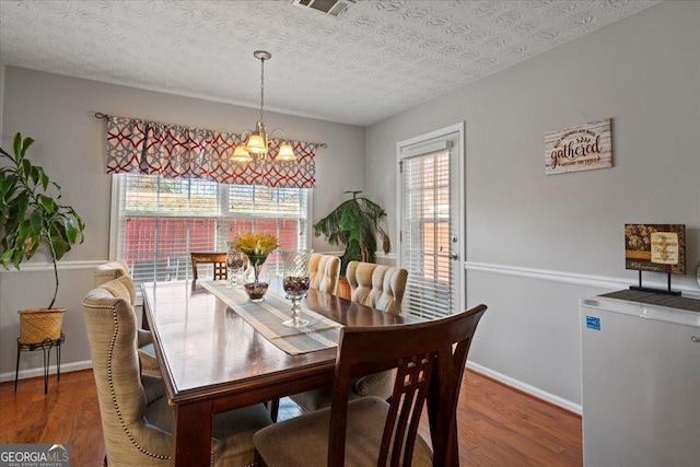 dining space with a textured ceiling, plenty of natural light, and dark wood-type flooring