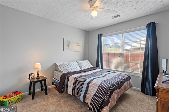 bedroom featuring ceiling fan, light colored carpet, and a textured ceiling