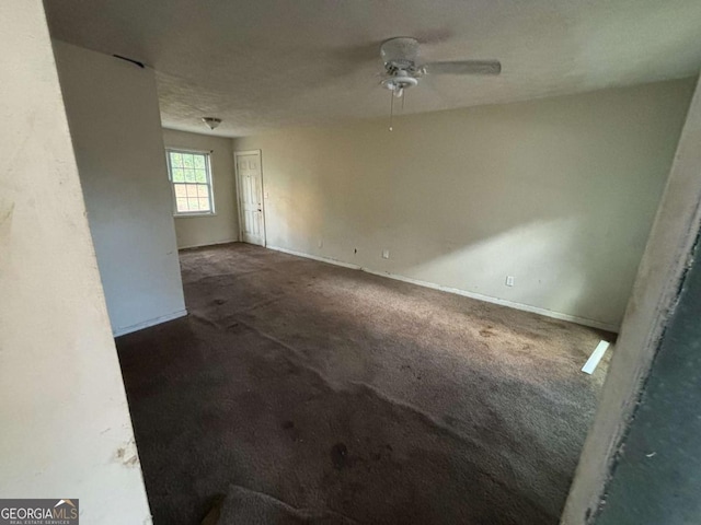 empty room with ceiling fan, dark carpet, and a textured ceiling