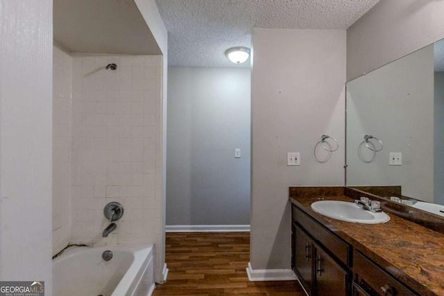 bathroom featuring hardwood / wood-style floors, vanity, a textured ceiling, and tiled shower / bath