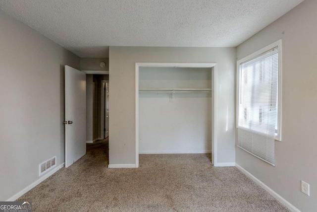 unfurnished bedroom with light colored carpet, a textured ceiling, and a closet