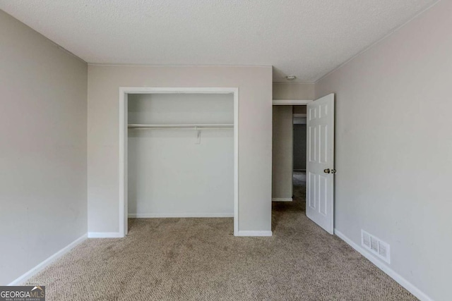 unfurnished bedroom with a textured ceiling, light carpet, and a closet