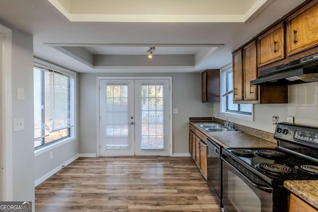 kitchen with french doors, a raised ceiling, sink, black appliances, and light hardwood / wood-style flooring