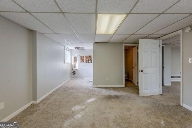 basement with a drop ceiling and light carpet