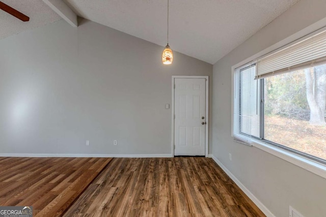 unfurnished dining area with vaulted ceiling with beams, dark hardwood / wood-style floors, and a textured ceiling