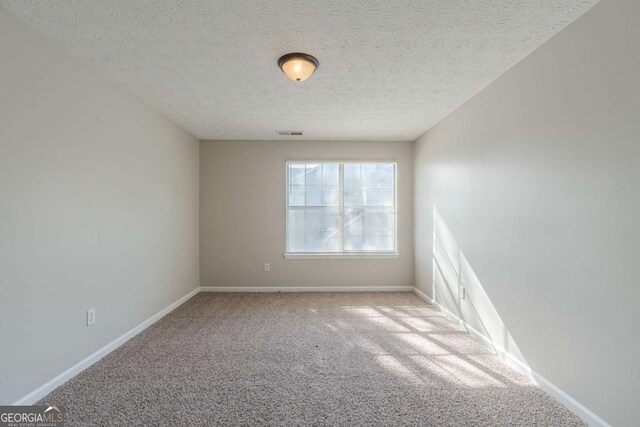 empty room featuring carpet and a textured ceiling