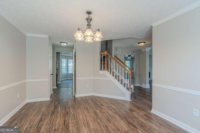 empty room with a textured ceiling, dark hardwood / wood-style flooring, and crown molding