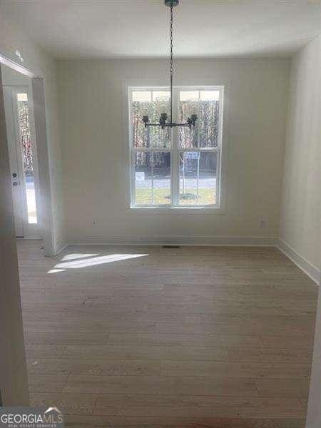 unfurnished dining area with a notable chandelier and hardwood / wood-style flooring