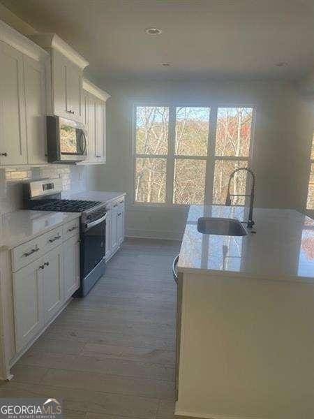 kitchen with dark hardwood / wood-style flooring, white cabinetry, sink, and appliances with stainless steel finishes