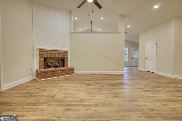 unfurnished living room with ceiling fan, a fireplace, high vaulted ceiling, and light wood-type flooring