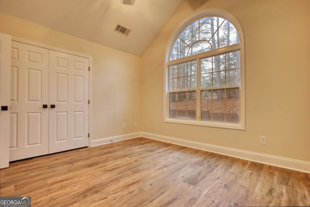 unfurnished room featuring light hardwood / wood-style flooring and lofted ceiling