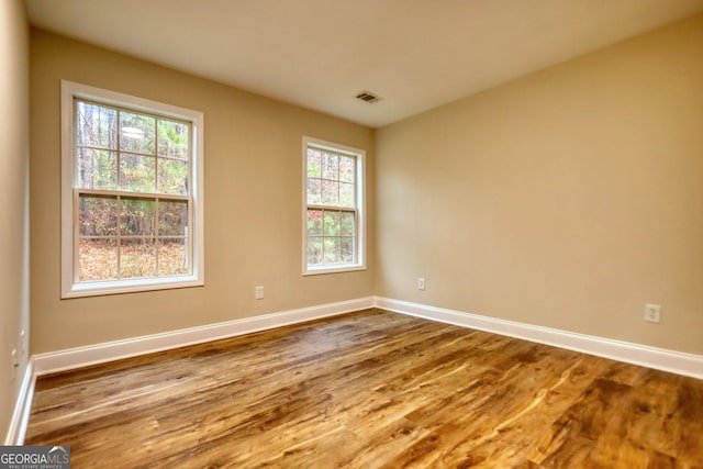 empty room with hardwood / wood-style floors and a healthy amount of sunlight