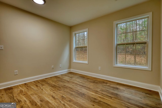 empty room featuring plenty of natural light and hardwood / wood-style flooring