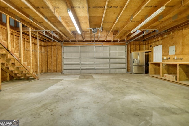 garage with stainless steel fridge and a garage door opener