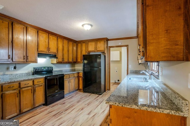 kitchen featuring black appliances, crown molding, sink, light stone countertops, and light wood-type flooring