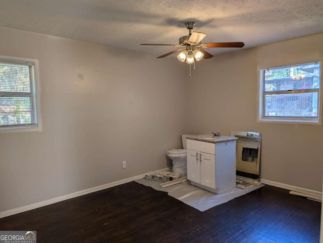 unfurnished room featuring a textured ceiling, ceiling fan, sink, and dark hardwood / wood-style floors