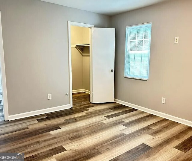 unfurnished bedroom featuring hardwood / wood-style floors, a spacious closet, and a closet