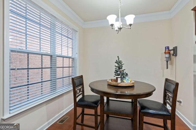 dining area featuring dark wood-type flooring, crown molding, and an inviting chandelier