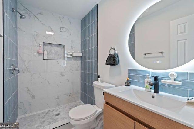 bathroom with tiled shower, vanity, tasteful backsplash, and toilet